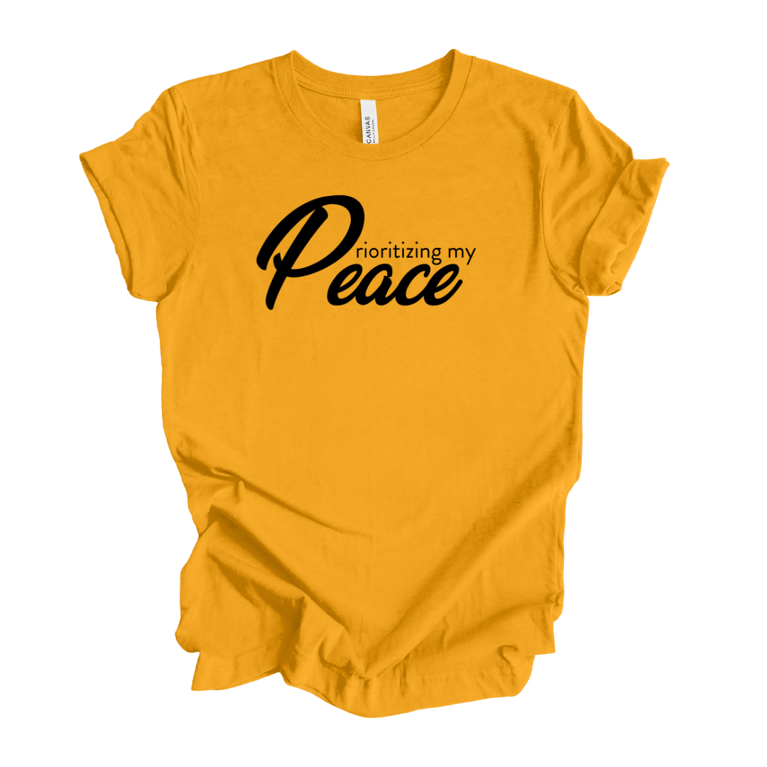 Gold unisex T-shirt with the words " Prioritizing my peace" on the front of it in black letters