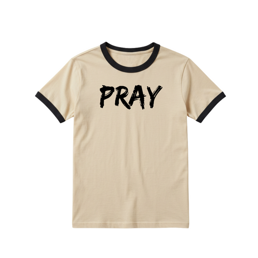 Beige Christian T-shirt with black ringer trim and bold black text reading “PRAY,” minimalist faith-based tee for everyday wear.